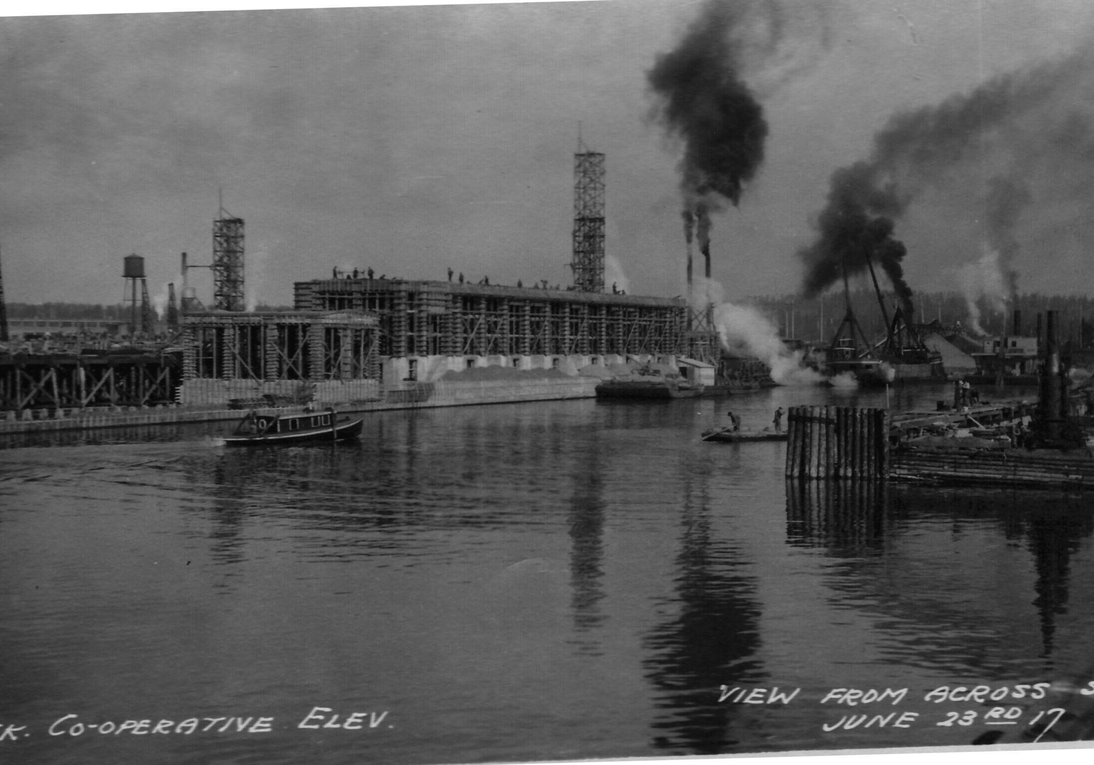 black and white image of the elevator across the water - smoke leaving the elevator in use