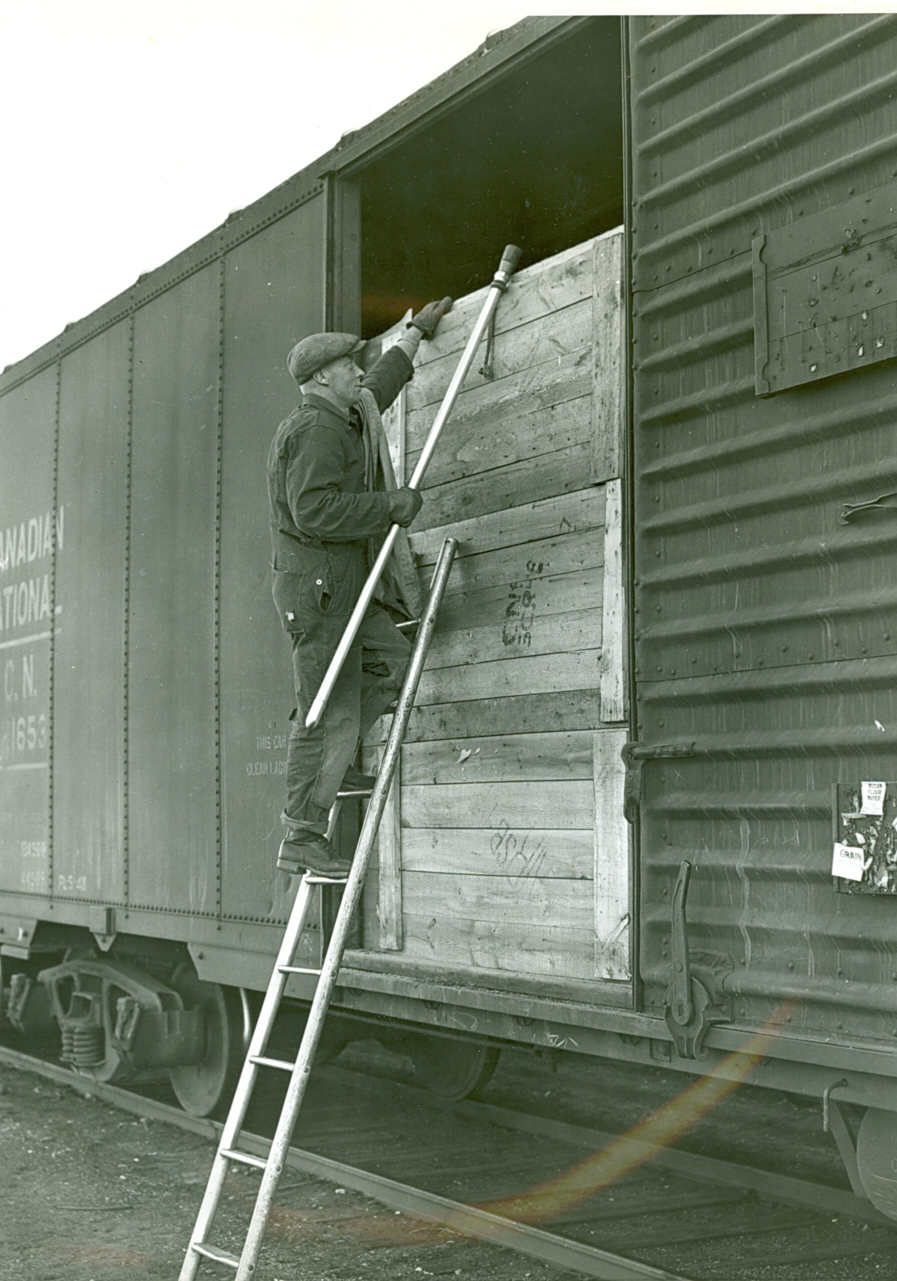 8 x 10 b &amp; w, showing sampler climbing ladder to enter car. He is holding a piece of cloth that appeared on top of the grain in a previous slide. What is the cloth for?