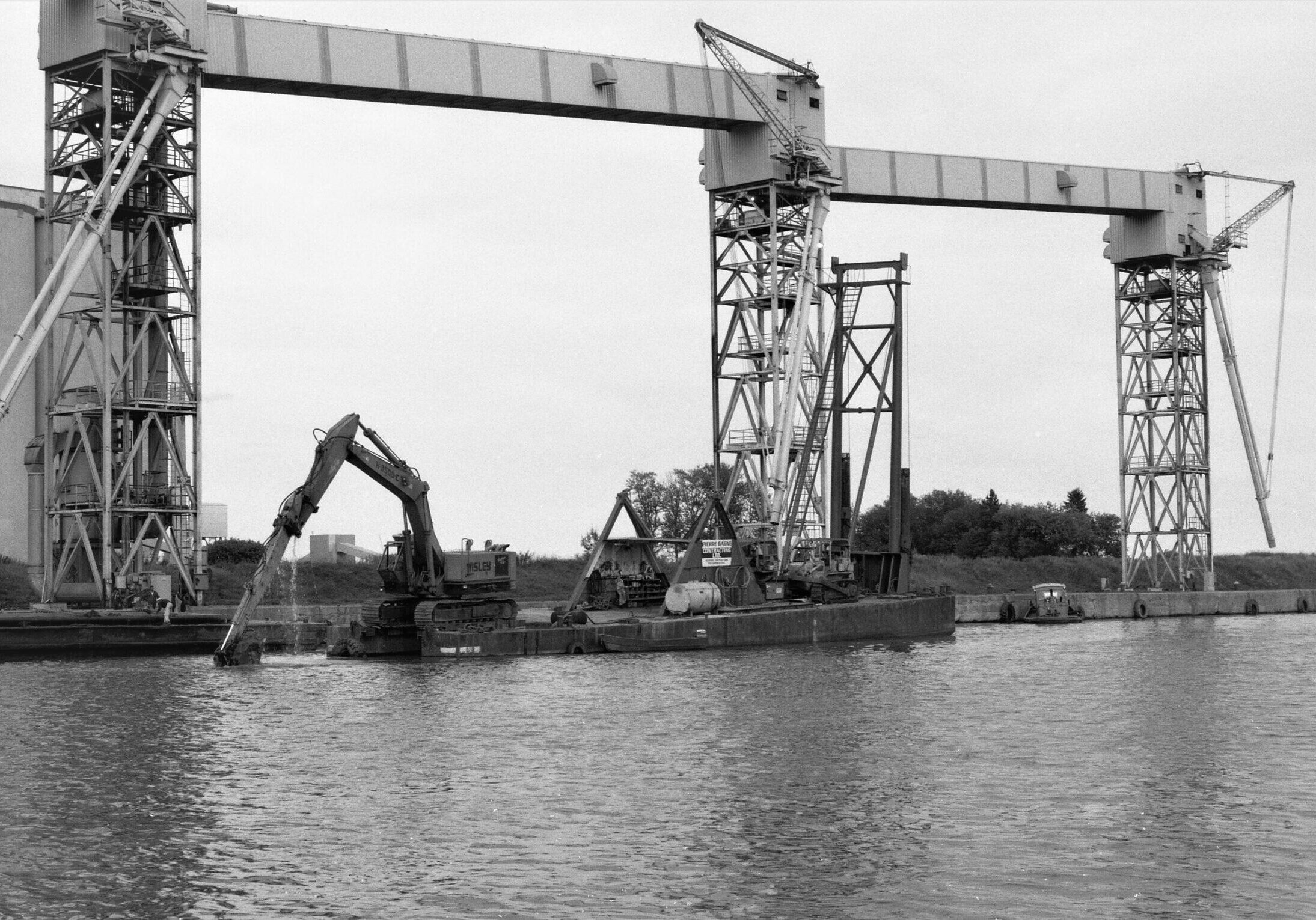 black and white image of lake and arms and trunk dredging up the port